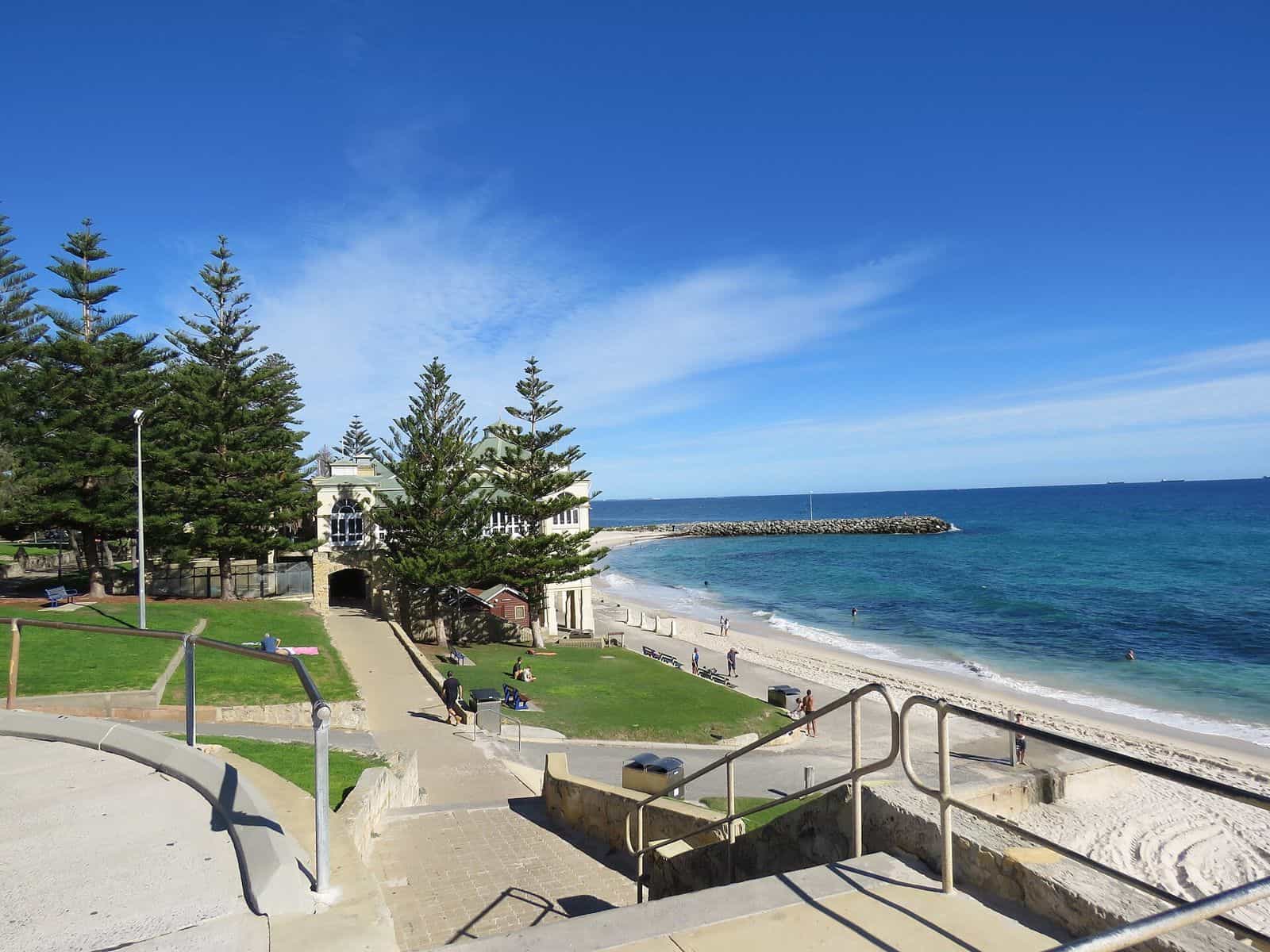Steps leading down past a grassy terrace and Norfolk Island pines to the sand at Cottesloe Beach