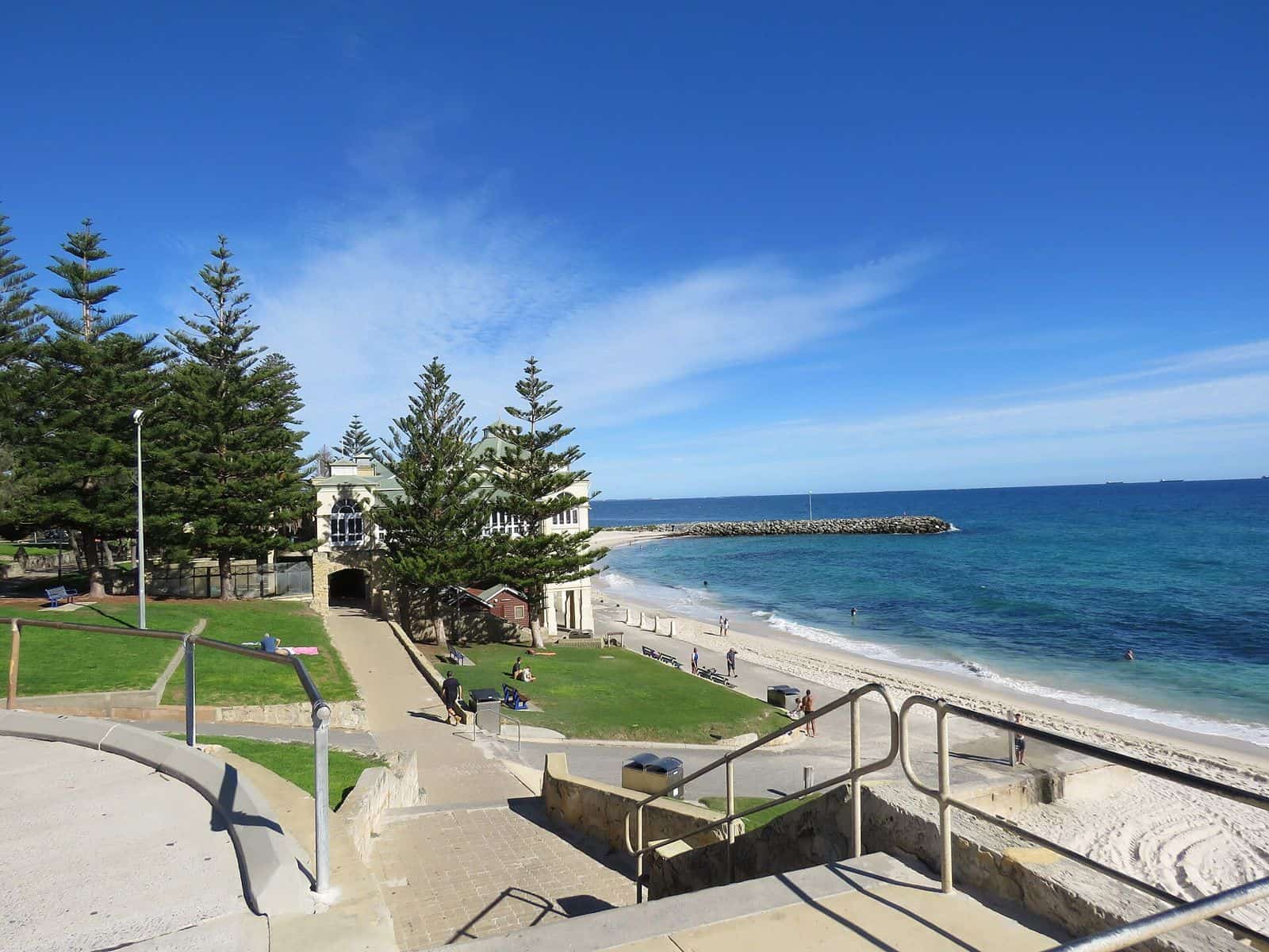 Steps leading down past a grassy terrace and Norfolk Island pines to the sand at Cottesloe Beach