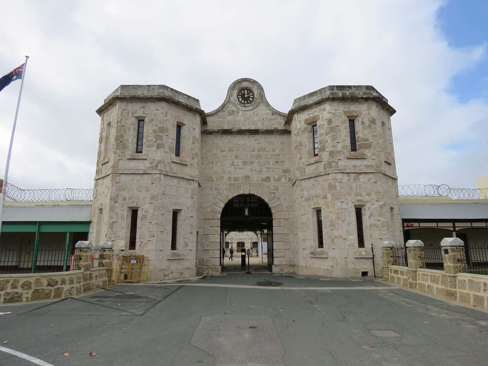 The pale limestone gatehouse and clock of Fremantle Prison under a blue sky
